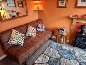 un sofá marrón en una sala de estar con almohadas. en Bray Cottage, en Sidmouth