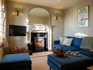 a living room with a blue couch and a fireplace at Rose Cottage, Rodborough in Stroud