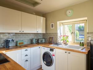 een keuken met een wasmachine en een wastafel bij Rose Cottage, Rodborough in Stroud