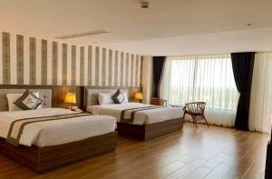 um quarto de hotel com duas camas e uma mesa em UM-PQ hotel Phú Quốc em Phu Quoc