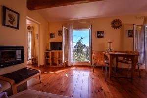 ein Wohnzimmer mit Holzboden, einem Tisch und einem Fenster in der Unterkunft Cottage provencal - Villa saint Marc in Forcalquier