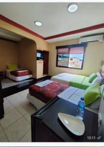 Un dormitorio con 2 camas y un escritorio con una botella de agua. en Hotel Los Algarrobos, en Puerto Baquerizo Moreno