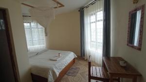 um pequeno quarto com uma cama e 2 janelas em Lago Resort - Best Views in Kisumu em Kisumu