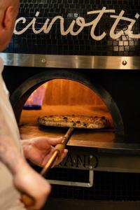 una persona sacando una pizza de un horno en Mandachi Hotel & SPA, en Suceava