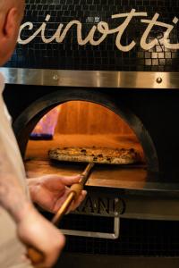 uma pessoa a tirar uma pizza de um forno em Mandachi Hotel & SPA em Suceava