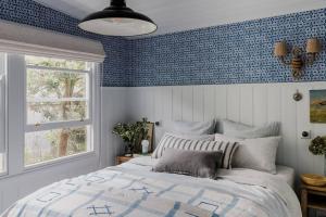 - une chambre avec un lit et un mur bleu dans l'établissement Port Cottage on the Great Ocean Road, à Port Campbell