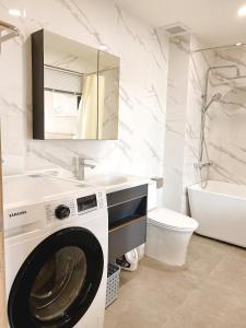 a washing machine in a bathroom with a sink and a tub at PH Hotel & Apartment in Hai Phong