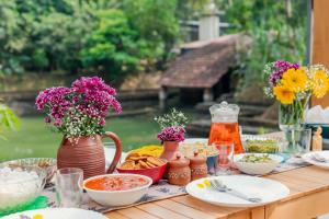 a wooden table with food and flowers on it at SaffronStays Amaya, Kannur - 300 years old heritage estate for families and large groups in Kannur