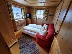 a small room with a bed and a red couch at Waschhütte, Ferienhaus in Finkenberg