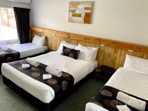 um quarto de hotel com duas camas com lençóis brancos em Motel Stawell em Stawell