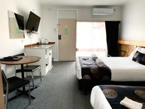 ein Hotelzimmer mit 2 Betten, einem Schreibtisch und einem Tisch in der Unterkunft Motel Stawell in Stawell