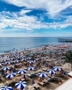 a beach with blue and white umbrellas and the ocean at Hotel Maremola in Pietra Ligure