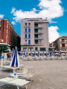 a group of beach chairs and umbrellas in front of a building at Hotel Maremola in Pietra Ligure