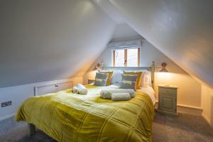 a bedroom with a large bed with yellow blankets and pillows at Pondside Barn in Long Wittenham