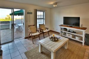 a living room with a television and a table at Birds View Holiday Home in Langebaan