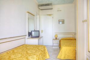 una camera d'albergo con due letti e una televisione di Hotel Elpiro a Lido di Jesolo