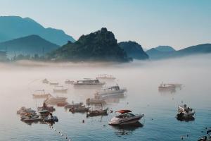 a group of boats in the water in the fog at Apartments First Line in Petrovac na Moru