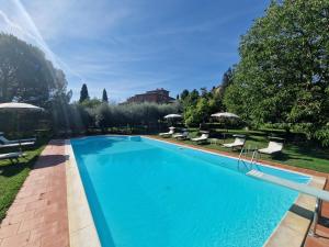 una gran piscina azul con sillas y sombrillas en Villa Vignacce - Boutique Country Resort, en Bettolle