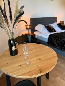 a wooden table with two wine glasses and a vase at Apartament Pobierowo PINEA in Pobierowo