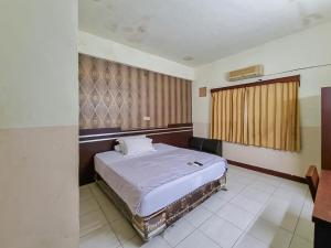 帕朗卡拉亚Hotel Halmahera Palangkaraya Mitra RedDoorz的房间里有一张大床的卧室