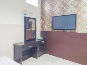 a bedroom with a tv and a dresser with a mirror at Hotel Halmahera Palangkaraya Mitra RedDoorz in Palangkaraya