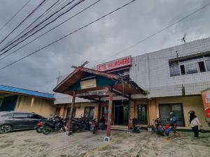 a gas station with motorcycles parked in front of a building at Hotel Halmahera Palangkaraya Mitra RedDoorz in Palangkaraya