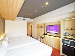 a bedroom with a bed and a flat screen tv at CHISUN PREMIUM Kyoto Kujo in Kyoto