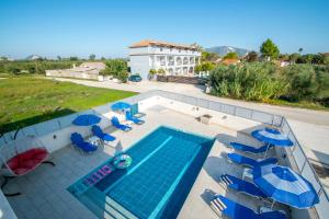 a swimming pool with chairs and umbrellas and a house at DENNIS and TANYA VILLAS in Laganas