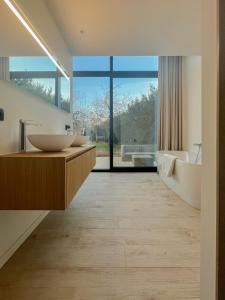 La salle de bains est pourvue de 2 lavabos et d'une grande fenêtre. dans l'établissement de Bosch, à Lummen
