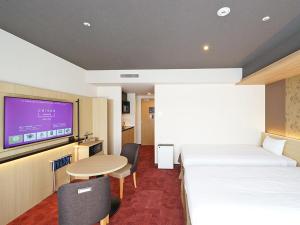 a hotel room with two beds and a table and a tv at CHISUN PREMIUM Kyoto Kujo in Kyoto