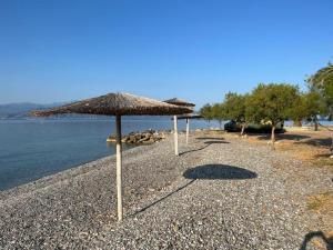 a beach with two umbrellas and the water at Nafpaktos Shingle Villa in Nafpaktos