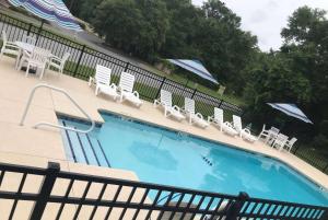 a swimming pool with chairs and umbrellas at Baymont by Wyndham Lake Park Valdosta I75 in Lake Park