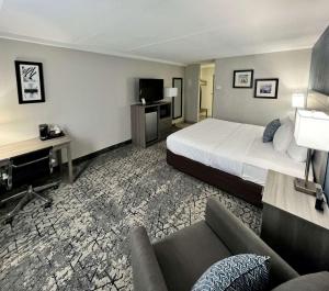 Clarion Hotel & Convention Center Joliet في جوليت: غرفه فندقيه بسرير واريكه