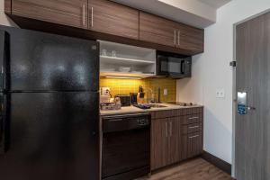 a kitchen with a black refrigerator and a sink at MainStay Suites Colorado Springs East - Medical Center Area in Colorado Springs