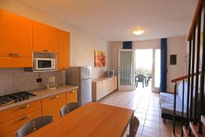 uma cozinha com armários laranja e uma mesa e uma cozinha com uma sala de jantar em Pini Village Lido Altanea em Caorle