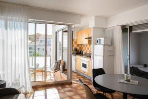 eine Küche mit einem Tisch und ein Esszimmer mit Aussicht in der Unterkunft Résidence Pierre & Vacances Les Bulles de Mer in Saint-Cyprien