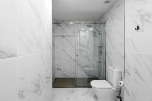 La salle de bains blanche est pourvue d'une douche et de toilettes. dans l'établissement Urban House by LovelyStay, à Porto