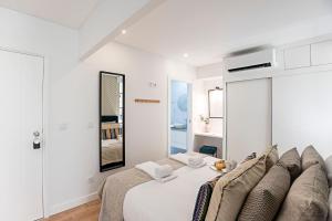 ein weißes Schlafzimmer mit einem Bett und einem Spiegel in der Unterkunft Urban House by LovelyStay in Porto