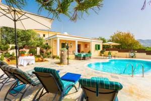 een zwembad met stoelen en een parasol en een huis bij Villa Constantinos in Kato Yialia
