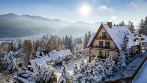 dom pokryty śniegiem w górach w obiekcie Aparthotel Delta Top w mieście Kościelisko