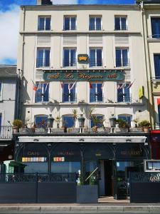 un grand bâtiment blanc avec drapeaux devant lui dans l'établissement Logis HOTEL RESTAURANT La Régence, à Cherbourg en Cotentin