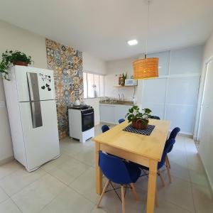 a kitchen with a wooden table and a white refrigerator at Casa Romão I - Charme perto de Vinícola e Centro in Espirito Santo Do Pinhal