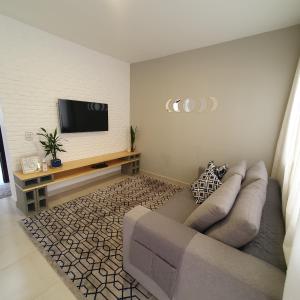 a living room with a couch and a flat screen tv at Casa Romão I - Charme perto de Vinícola e Centro in Espirito Santo Do Pinhal