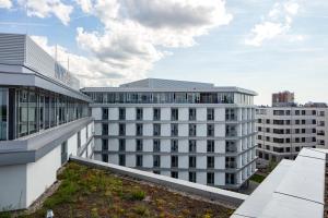 een wit gebouw met een groen dak in een stad bij Black F House - Serviced Apartments in Freiburg im Breisgau