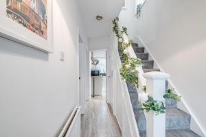 a staircase with white walls and white stairs with plants at 4 Bedroom House Near BHX, NEC & HS2 in Birmingham