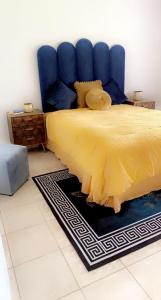 a bedroom with a yellow bed with a blue headboard at Ntindili Bed and Breakfast in De Deur