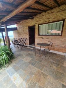 um pátio com cadeiras, uma mesa e uma parede de tijolos em Pousada Mirante Serra Verde em Carrancas