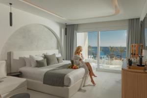 White Hills Resort في شرم الشيخ: امرأة جالسة على سرير في غرفة فندق