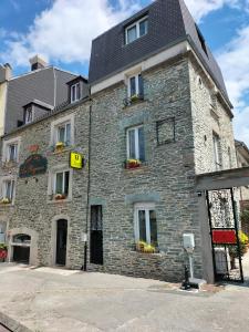 - un vieux bâtiment en pierre avec des fleurs aux fenêtres dans l'établissement Logis HOTEL RESTAURANT La Régence, à Cherbourg en Cotentin