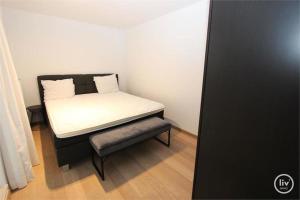 een kleine slaapkamer met een bed en een stoel bij Appartement spacieux à Knokke in Knokke-Heist